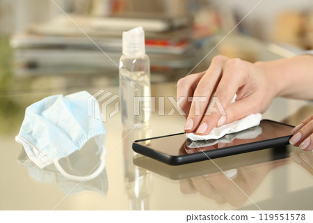 Girl hand with mask disinfecting with sanitizer phone screen 119551578