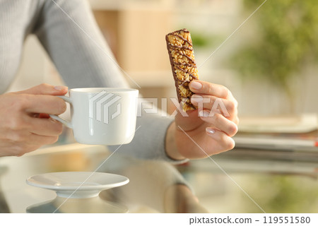 Girl hands holding snack bar and coffee cup at breakfast 119551580