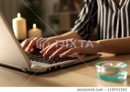 Girl hands typing on laptop on power outage with candles 119551583