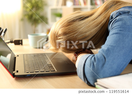 Overworked tired student sleeping over desk at home 119551614