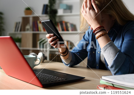 Sad student reading bad news on phone at night Sad student reading bad news on phone at night 119551624