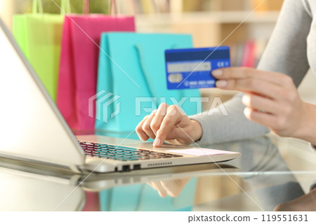 Shopper hands buying with credit card on laptop Shopper hands buying with credit card on laptop 119551631