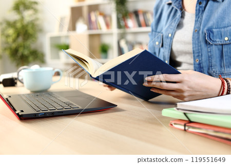 Student girl hands reading hard cover book at home 119551649