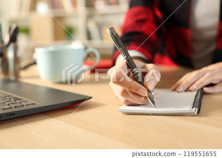 Student girl hands taking notes on notebook on a desk 119551655