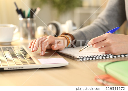 Student hands comparing notes on notebook with laptop 119551672