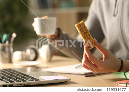 Student hands holding coffee and bar at night studying 119551677