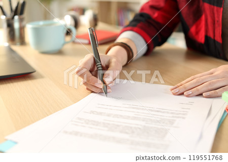 Student hands signing contract sitting at home 119551768