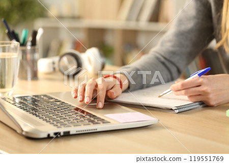 Student hands studying comparing notes with laptop 119551769