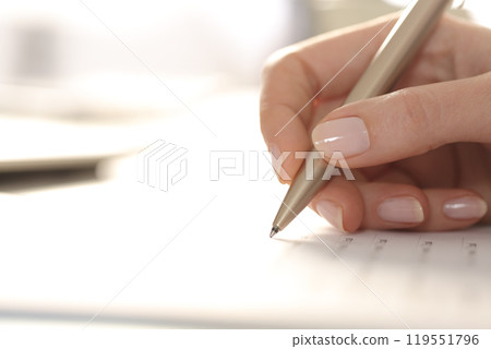 Woman hand filling out form with pen on a desk 119551796