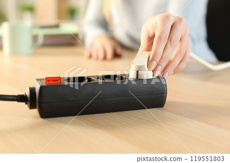 Woman hand plugging plug on a power strip socket 119551803
