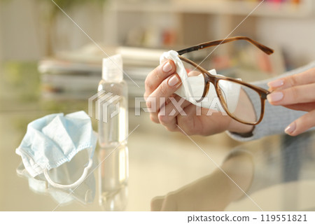 Woman hand with mask cleaning glasses with sanitizer Woman hand with mask cleaning glasses with sanitizer 119551821