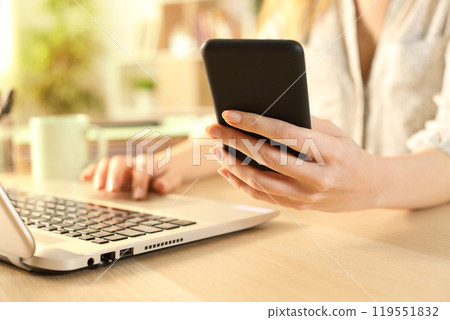 Woman hands checking phone using laptop 119551832