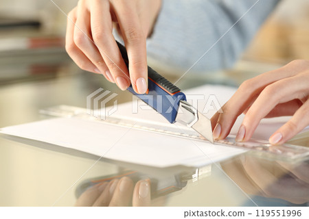Woman hands cutting paper with cutter and ruler Woman hands cutting paper with cutter and ruler 119551996