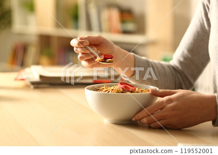 Woman hands eating breakfast cereal bowl at home 119552001