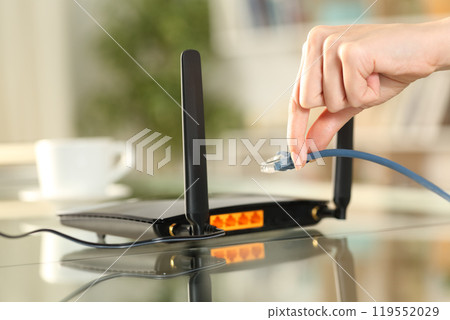 Woman hands plugging ethernet cable to router 119552029