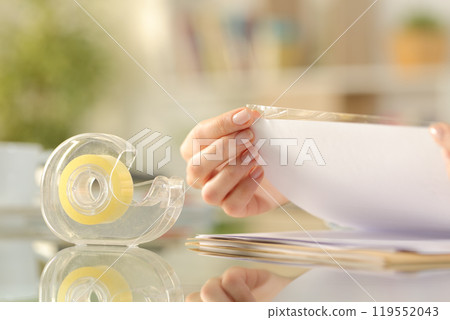 Woman hands sticking adhesive tape on a paper 119552043