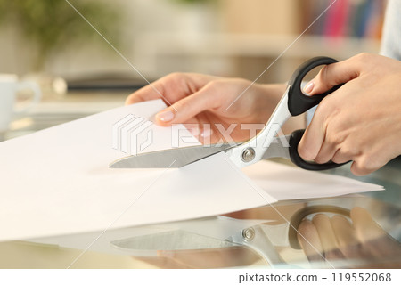 Woman hands with scissors cutting paper on a desk 119552068