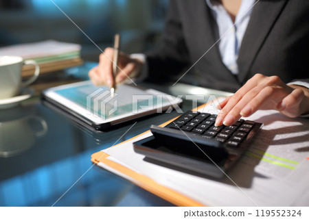 Businesswoman hands using tablet and calculator in the night Businesswoman hands using tablet and calculator in the night 119552324