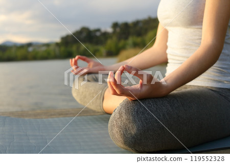 Close up of a woman practicing yoga in a lake 119552328