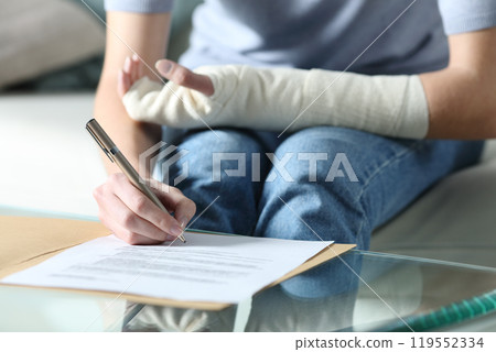 Disabled woman with bandaged arm sigining document 119552334