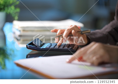 Executive hands calculating in the night at office Executive hands calculating in the night at office 119552345