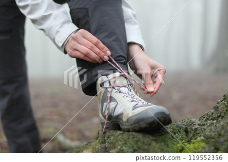 Hiker tying boot laces in the mountain 119552356