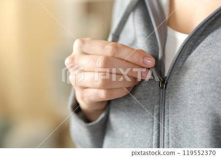 Teen hand closing zipper of gray hoodie at home 119552370