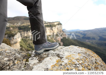 Trekker boot in the top of a cliff in the mountain 119552376