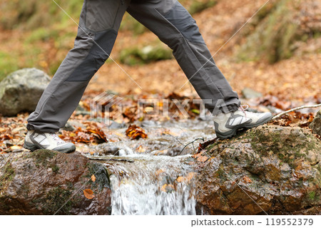 Trekker walking crossing a river in winter 119552379
