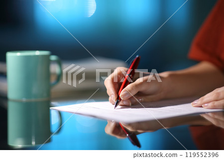 Woman hand filling out form in the night at home Woman hand filling out form in the night at home 119552396