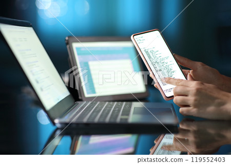 Woman hand using multiple devices at home in the night 119552403