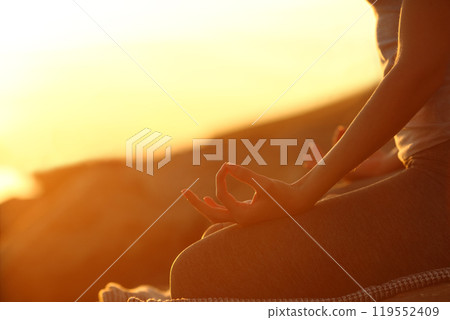 Woman hands at sunset practicing yoga exercises Woman hands at sunset practicing yoga exercises 119552409