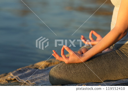 Woman hands at sunset practicing yoga on the beach Woman hands at sunset practicing yoga on the beach 119552410