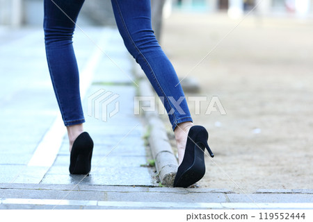 Woman legs with high heels stumbling in the street Woman legs with high heels stumbling in the street 119552444