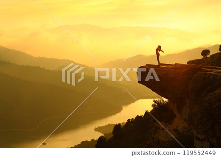 Woman silhouette breathing fresh air in the top of a cliff Woman silhouette breathing fresh air in the top of a cliff 119552449