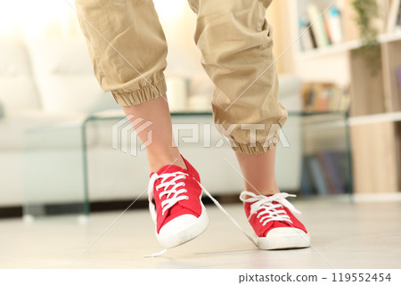 Woman stumbling with shoelaces at home Woman stumbling with shoelaces at home 119552454