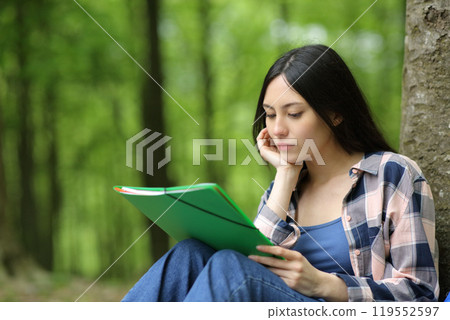 Asian student studying reading notes in a park Asian student studying reading notes in a park 119552597