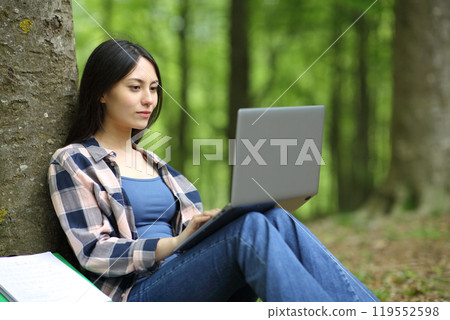 Asian student using laptop in a forest 119552598