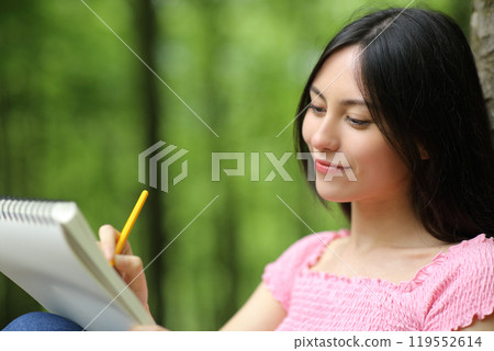 Asian woman drawing on notebook in a park 119552614