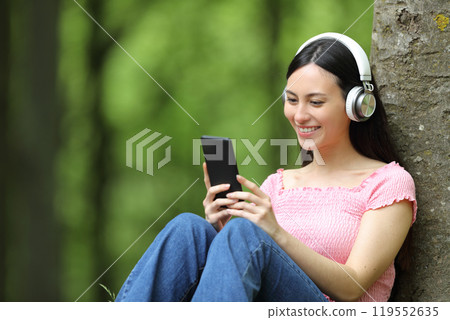 Asian woman listening to music sitting in a forest 119552635