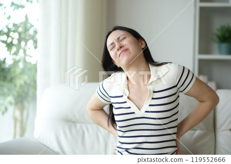 Asian woman suffering lumbago on uncomfortable couch 119552666