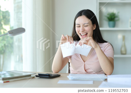Happy asian woman breaking receipt or bill at home Happy asian woman breaking receipt or bill at home 119552703