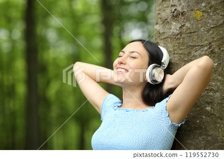 Happy asian woman listening to music in a park 119552730