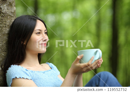 Happy asian woman looking away and drinking coffee 119552732