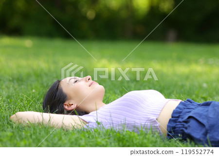 Mixed race woman relaxing lying on the grass 119552774