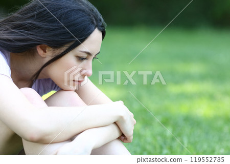 Sad asian woman complaining alone in a park Sad asian woman complaining alone in a park 119552785