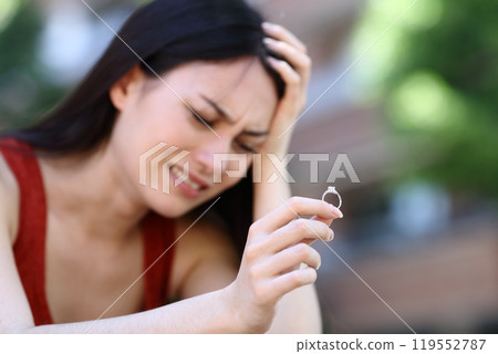 Sad asian woman complaining holding engagement ring Sad asian woman complaining holding engagement ring 119552787