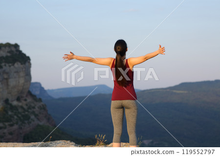 Sportswoman outstretching celebraing in the mountain 119552797