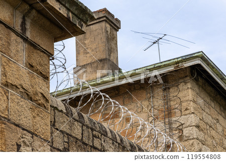 Barbed wire fence on high wall perimeter for security and protection 119554808