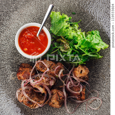 Grilled meat with red onions and herbs served on plate with tomato sauce Grilled meat with red onions and herbs served on plate with tomato sauce 119555604